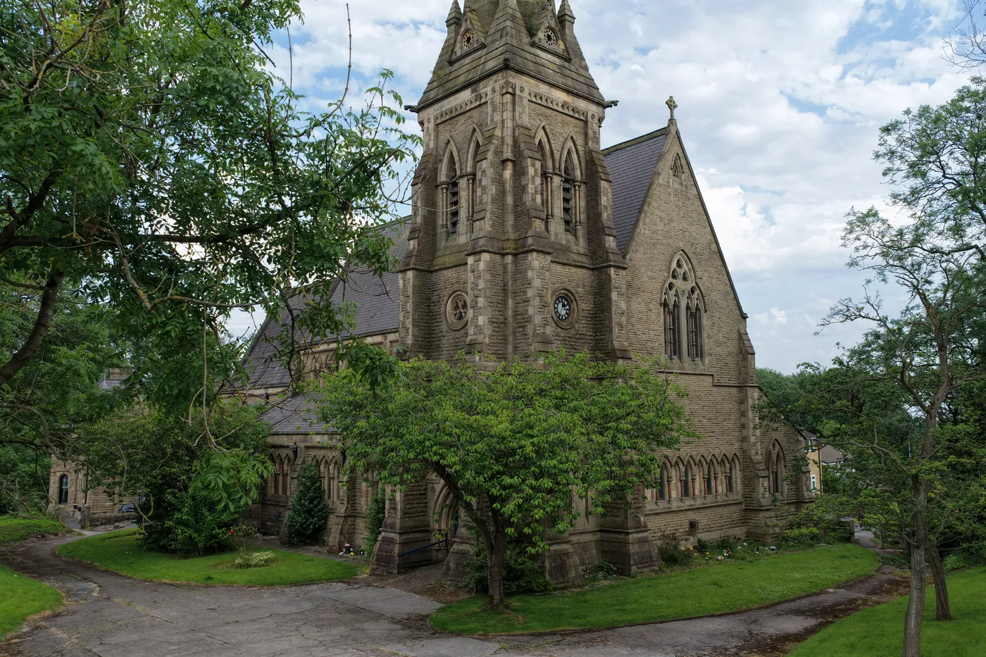 St Thomas from its own churchyard, tower and spire rising above summer trees