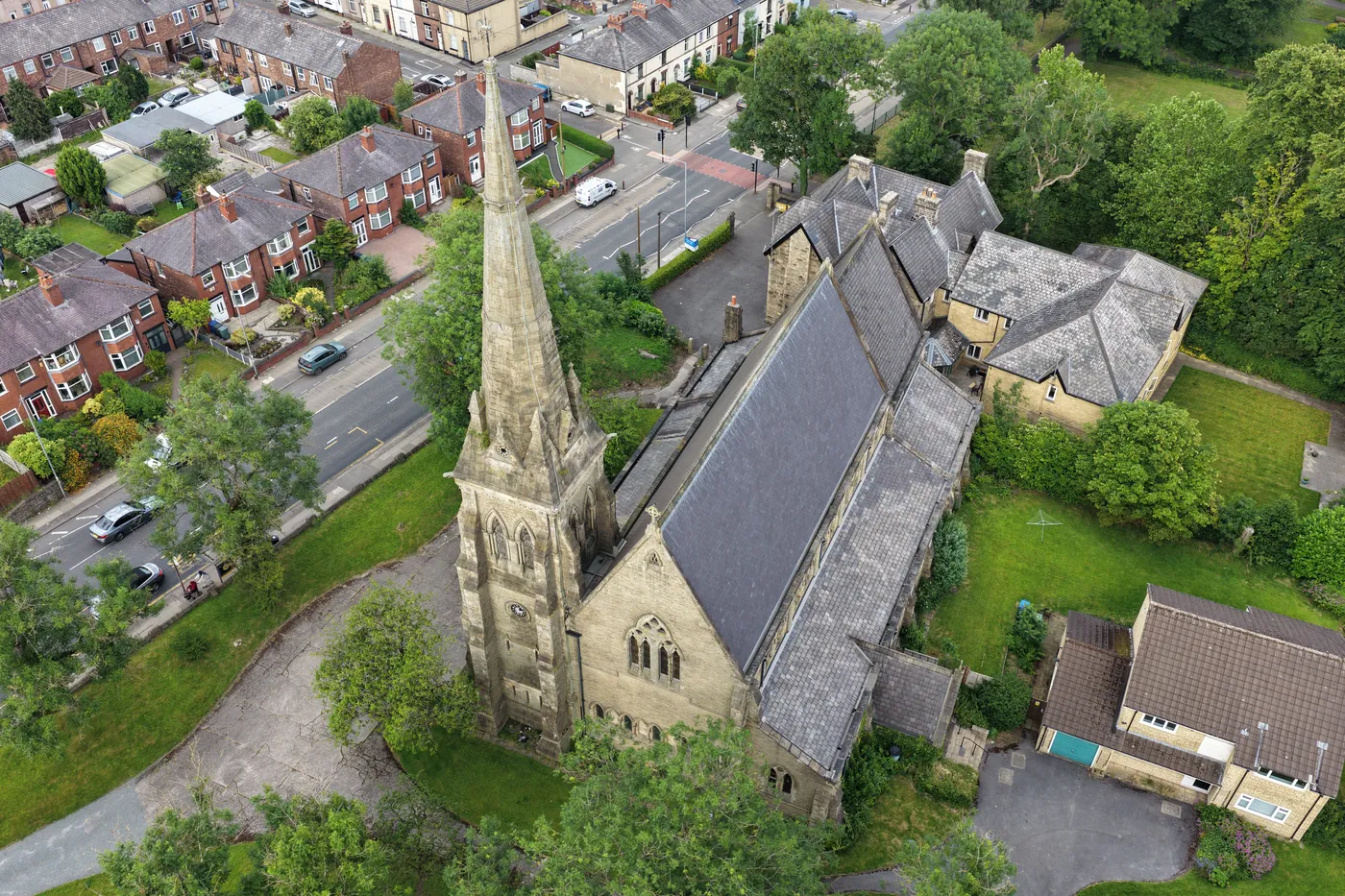 Overhead view of the slate roof, spire and parish buildings of St Thomas beside the road