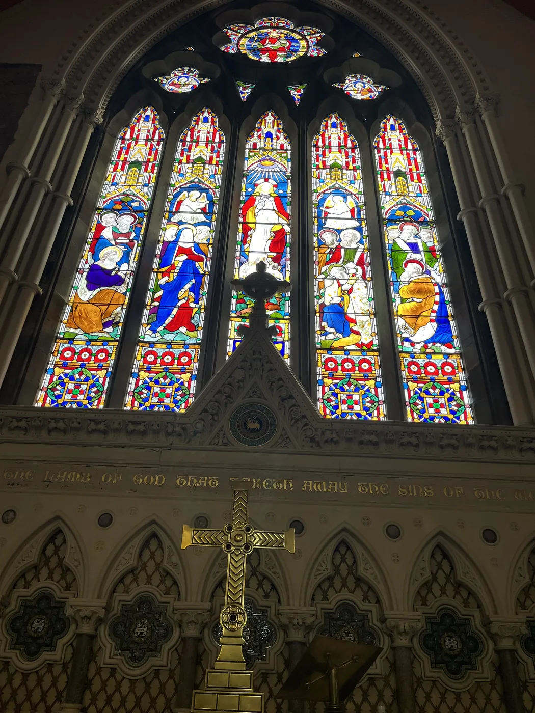 Tall stained-glass east window above the carved reredos