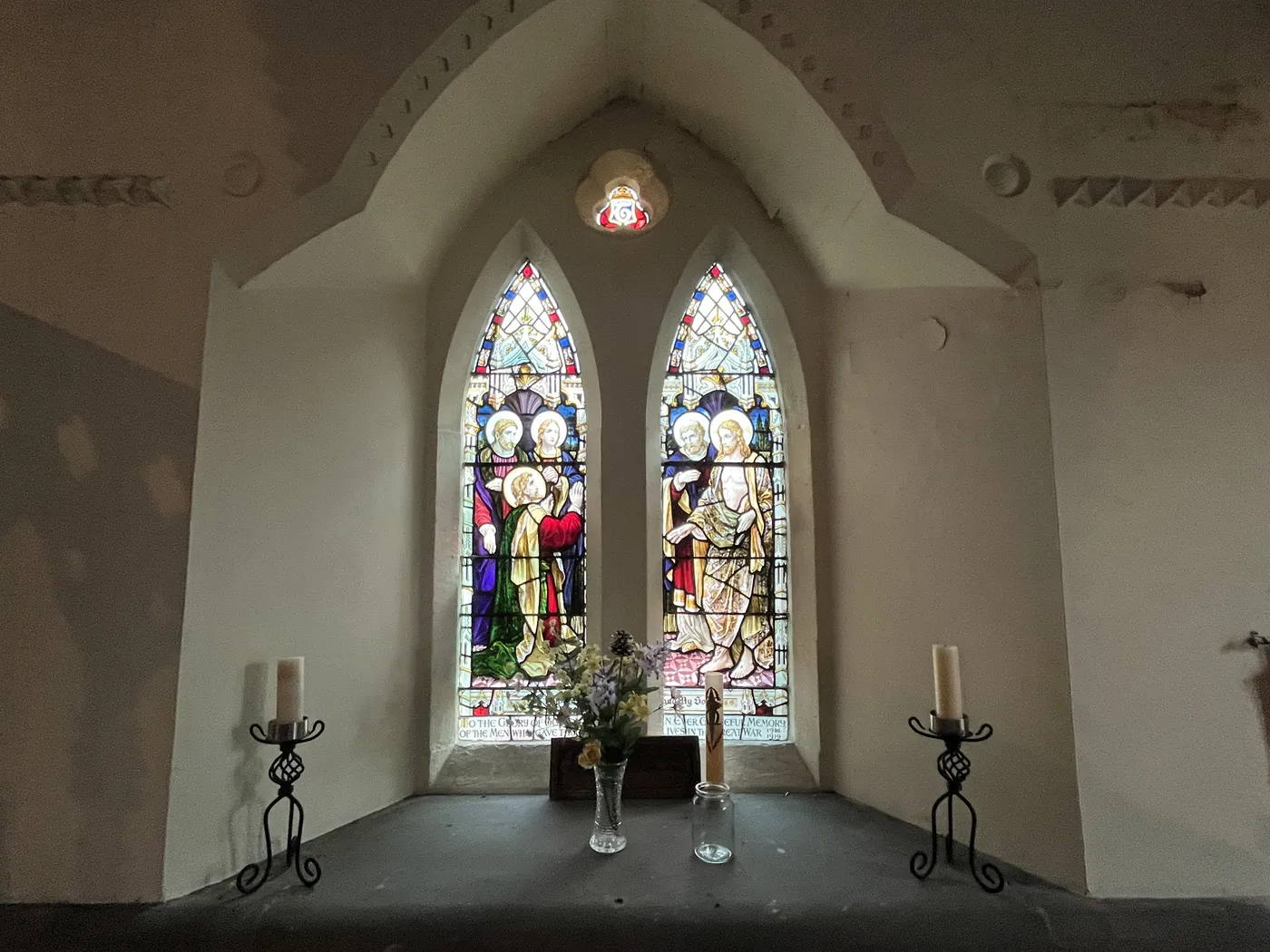 Paired stained-glass windows with flowers and candle stands