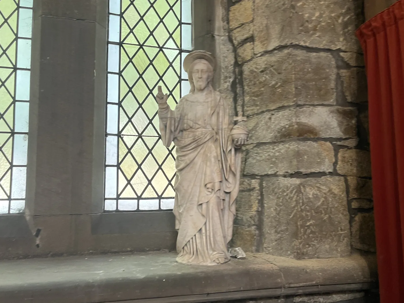 Stone figure of Christ beside a leaded window