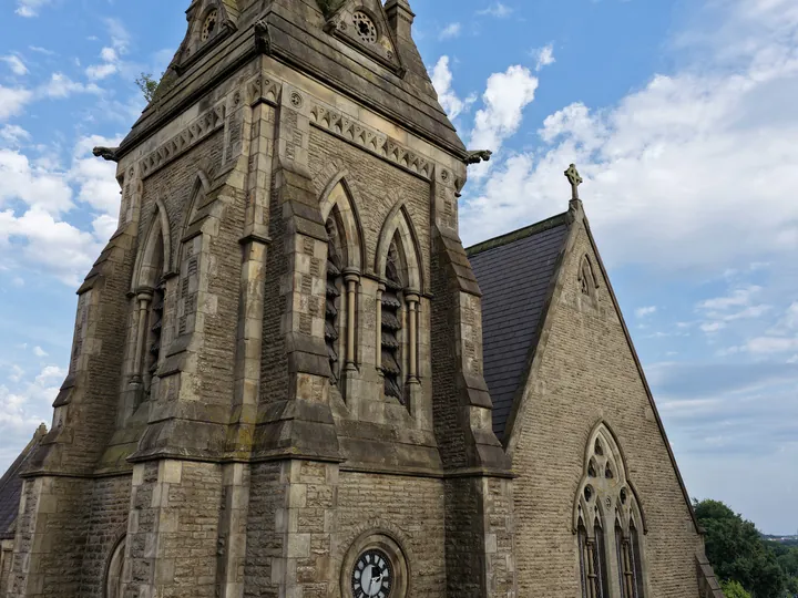 The tower and paired belfry openings of St Thomas seen steeply from below