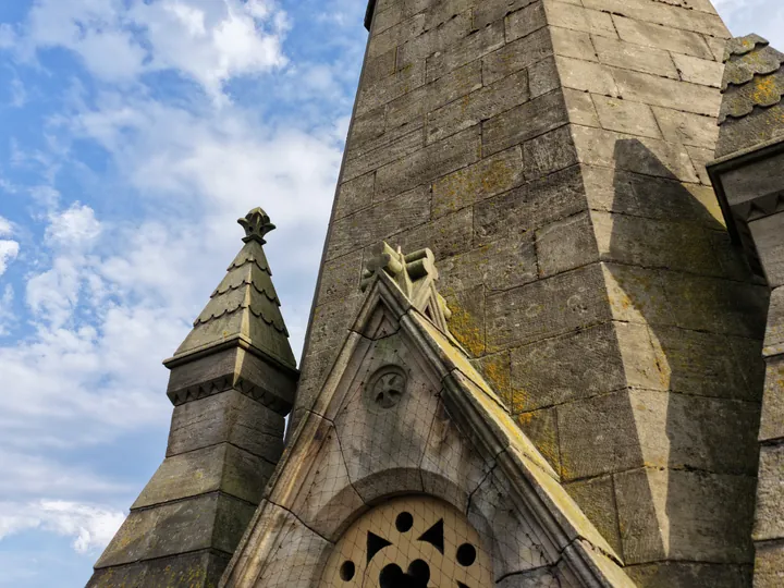 A carved stone figure set at the foot of the spire, far above head height