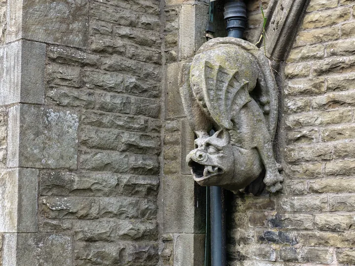 A winged stone grotesque projecting from the wall to throw rainwater clear of the stonework