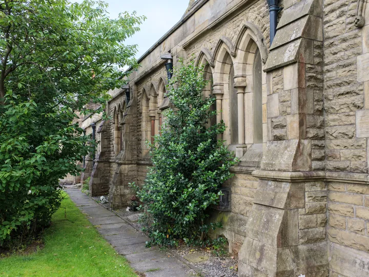 A stone path running beside the arcaded south wall between shrubs and lawn