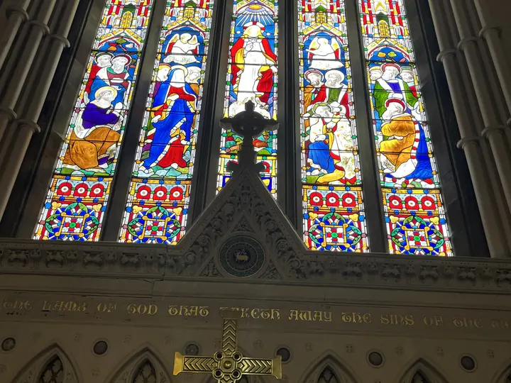 Tall stained-glass east window above the carved reredos