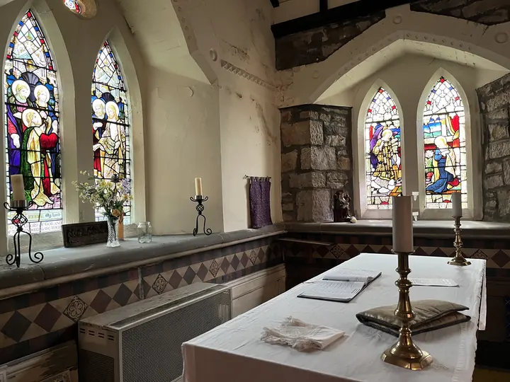 Side chapel altar framed by stained-glass lancet windows