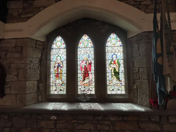 Three saintly figures depicted in stained glass