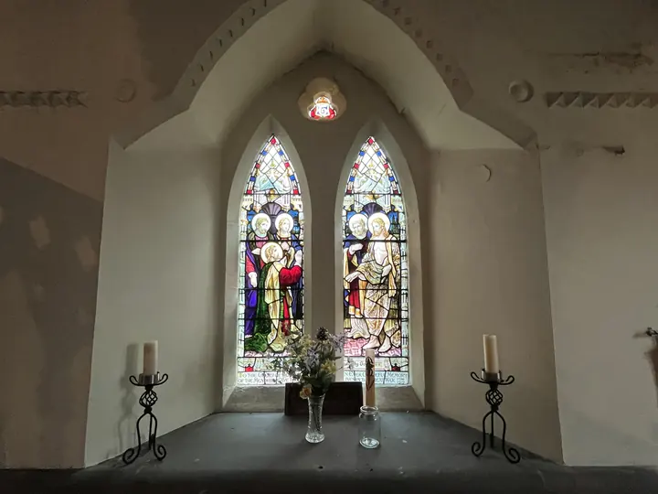 Paired stained-glass windows with flowers and candle stands