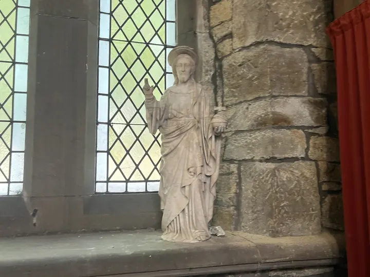 Stone figure of Christ beside a leaded window