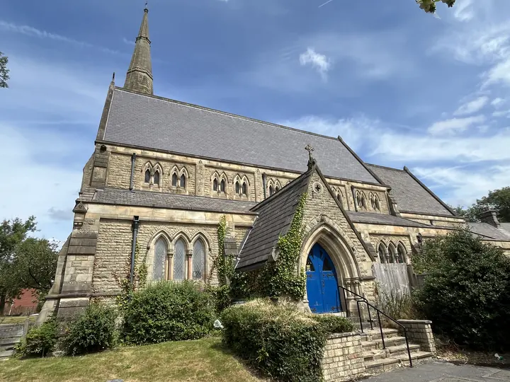 Stone exterior of St Thomas Church with blue door and spire